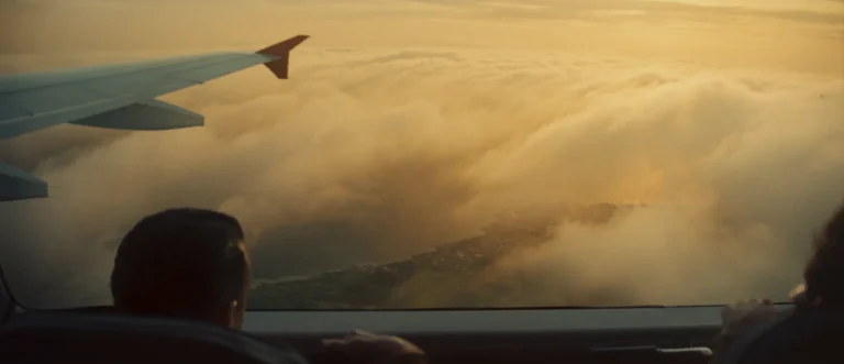 View over an aircraft wing above clouds at golden hour