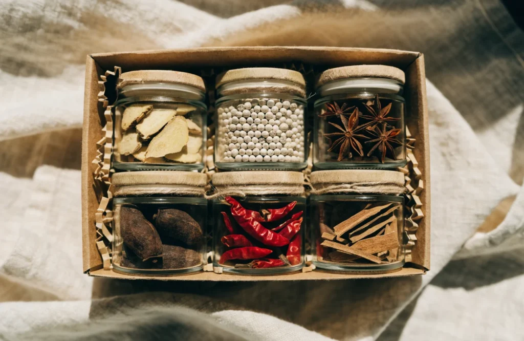 Six glass jars of whole spices in a box